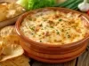 Prato de porcelana marrom com queijo gratinado e pedaços de salsinha picada.
