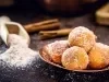 Em cima de uma mesa, prato com bolinhos de chuva, polvilhado com açúcar de confeiteiro.