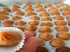 Foto em tons de laranja da receita de brigadeiro de churros servida em várias porções, com destaque para uma unidade sobre os dedos de uma pessoa a frente