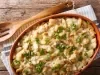 Em cima de uma mesa, recipiente com bacalhau e queijo gratinado, decorado com cebolinha picada.