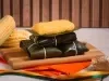 Pamonha de milho verde com erva-doce embrulhada em folhas de bananeira, corte cremoso sobre tábua