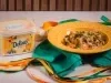 Baião de Dois junino cremoso com carne seca, bacon e calabresa servido em prato amarelo ao lado de Margarina Deline
