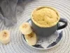 Imagem de um bolo de caneca com rodelas de banana ao lado.