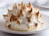 Baked Alaska individual com merengue tostado e textura cremosa servido em prato branco elegante