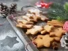 Em cima de uma mesa decorada com enfeites de natal, prato com biscoitos dourados e crocantes em formato de estrela, decorados com açúcar refinado.