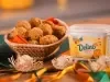 Bolinho de milho recheado com frango em cesta ao lado de pote de Margarina Deline