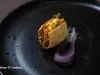 Crocante de tapioca recheado com carne de siri, maionese de butiá, ovas de tainha e brotos, servido em apresentação sofisticada.