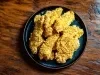 Fotografia vista de cima de uns peitos de frango empanados e crocantes, parte de uma receita de sambiquira.