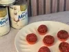 Docinhos de chocolate com granulado vermelho em forminhas vermelhas, servidos em prato claro com Leite Moça ao fundo.