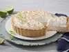 Imagem de uma torta de limão com merengue em um prato branco e uma fatia sendo retirado por uma espátula.
