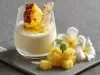 Imagem de um copo servido com um creme cremoso de abacaxi, decorado com uma fatia de abacaxi em meia-lua e lascas de coco.