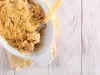 Fotografia em tons claros visto de cima de uma torta cremosa de farofa doce sobre um pano amarelo e branco dobrado, apoiado em uma mesa de madeira clara.