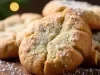 Em cima de uma mesa, biscoito crocante, polvilhado com açúcar de confeiteiro.
