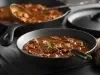 Ensopado de carne macia envolta em um molho avermelhado e espesso, servido em um prato fundo com salsinha picada por cima