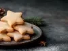 Em cima de uma mesa, prato redondo com biscoitos em formato de estrelas, decorados com açúcar de confeiteiro.