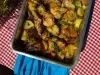 Frango assado dourado com batatas em rodelas levemente crocantes nas bordas, tudo coberto com cebolas caramelizadas e cheiro-verde fresco. Servido em assadeira rústica sobre mesa de madeira.