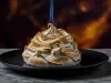 Baked Alaska de NINHO® com merengue maçaricado e chama azul sobre prato branco sofisticado