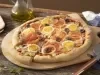 Imagem de uma pizza portuguesa redonda com queijo, tomate, cebola, ovo, azeitona preta sobre uma tábua de madeira.