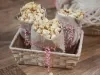 Imagem de uma cesta de palha com três saquinhos de papel com pipoca doce com Farinha Láctea Nestlé.