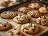 Imagem de uma assadeira com vários cookies com gotas de chocolate um ao lado do outro.