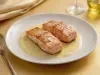 Filés de salmão grelhados servidos com molho cremoso claro e ervas, apresentados em prato raso com acabamento sofisticado.