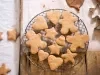 Em cima de uma mesa, grade com biscoitos em formato de coração, estrelas e bonecos de gengibre.