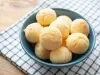 Imagem de um bowl azul sobre um pano xadrez com pães de queijo.