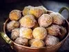 Em cima de uma mesa, balde de metal com bolinhos de chuva, polvilhado com açúcar de confeiteiro.