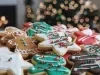 Em cima de uma mesa, prato redondo com biscoitos em formato de estrelas e boneco de gengibre, decorados com glacê colorido e confeitos coloridos na cores vermelho, verde e branco.