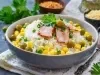 Em cima de uma mesa, tigela com porção de arroz branco soltinho com milho, azeitonas verdes, decorado com fatias de bacon e folha de salsa.