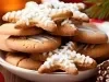 Em cima de uma mesa, prato com biscoitos em formato de estrelas e redondos, decorados com glacê branco.