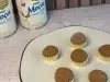 Seis brigadeiros em forminhas douradas sobre prato claro, com duas latas de LEITE MOÇA® ao fundo.