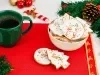 Em cima de uma mesa, tigela redonda com biscoitos em forma de árvore e diversas formas, decorados com glacê branco e confeitos coloridos de bolinha.