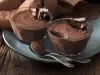 Foto de duas pequenas tigelas com mousse de chocolate dentro em cima de um prato azul