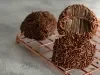 Imagem de três brigadeiros cobertos com chocolate granulado, com um brigadeiro mordido em destaque, mostrando a textura cremosa da receita.