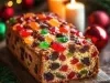Fotografia de um bolo de frutas natalino, ricamente decorado com frutas cristalizadas coloridas, apresentado em uma tábua de madeira rústica, cercado por velas que criam uma atmosfera acolhedora e festiva.