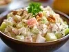 Em cima de uma mesa,  tigela com salada de maionese com cenouras, batatas, decoradas com nozes picadas e folha de cheiro-verde.