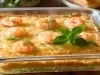 Fotografia mostra uma torta de camarão na travessa transparente com pequenos camarões decorando a crosta dourada da torta.