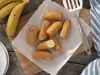 Imagem vista de cima de bananas a milanesa em cima de uma tábua de madeira