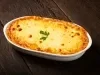 Fotografia mostra uma torta dourada, com a mussarela derretida e gratinada a coentro decorando.