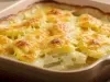 Em cima de uma mesa, refratário com batatas cremosas gratinadas com queijo.