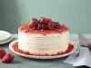 Imagem de um bolo red velvet inteiro decorado com frutas vermelhas. Ao lado, uma espátula, pratos e morangos.
