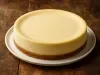 Fotografia da torta sem as frutas secas e damascos, como uma cheesecake sobre o prato raso branco.