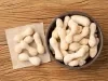 Imagem vista de cima de um bowl escuro com biscoitos de polvilho com um papel ao lado com mais biscoitos em cima.