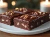 Fotografia de um prato com bolo de chocolate, cobertos com um brilho intenso e decorados com nozes. A luz suave das velas cria uma atmosfera convidativa e aconchegante.