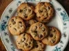 Em cima de uma mesa, prato redondo com biscoitos crocantes com gotas de chocolate.