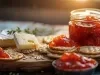 Imagem de um tábua de madeira com um pote de geleia de pimenta, queijos e biscoitos com geleia.
