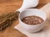 Receita de massa de brownie comestível servida em um pote branco sobre uma mesa de madeira decorada com alecrim