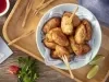 Imagem vista de cima de um bowl azul claro com bolinhos de peixe, garfos de madeira e pedaços de limão.