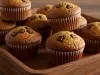 Em cima de uma mesa, cesta com bolinhos de fúba e chocolate picado derretido.